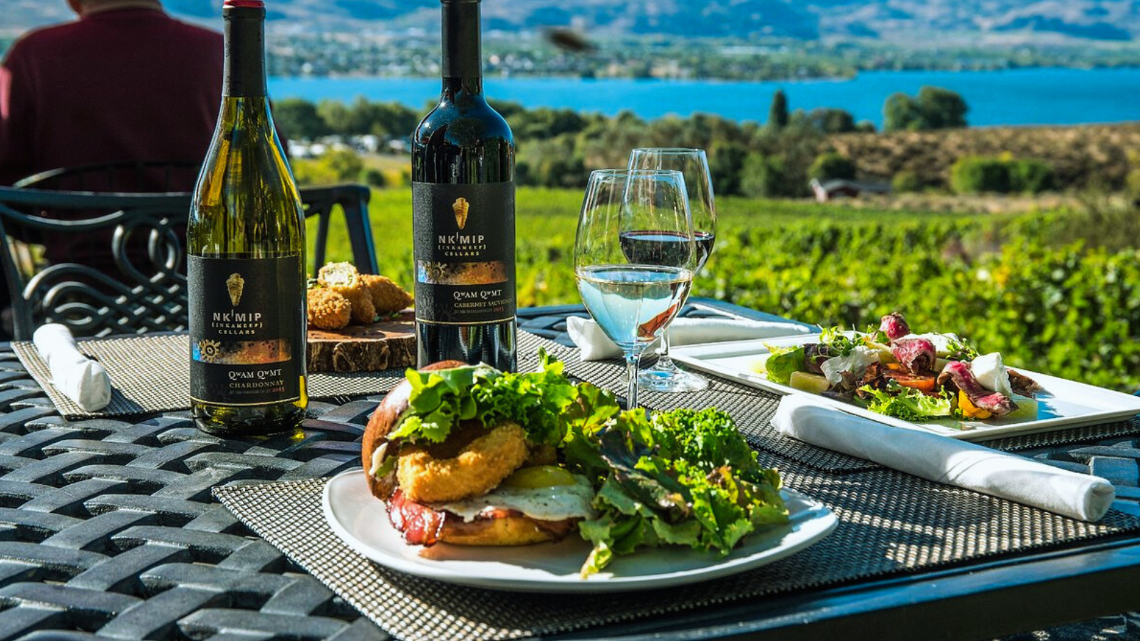 Sandwich, salad and wine on table overlooking water