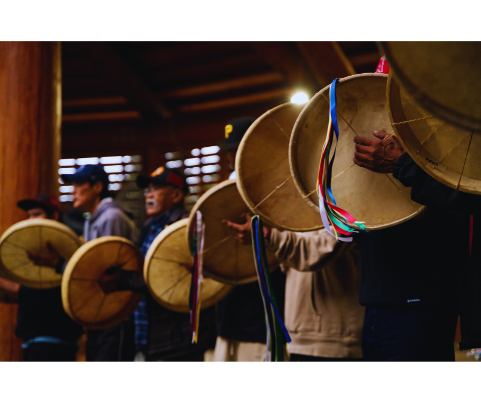 People holding large traditional drums with colorful ribbons.