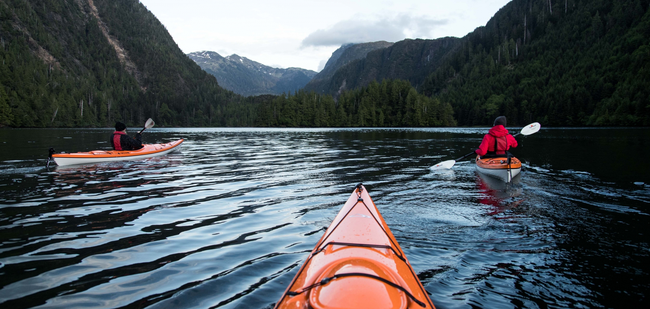 Three people kayaking on the mountains.