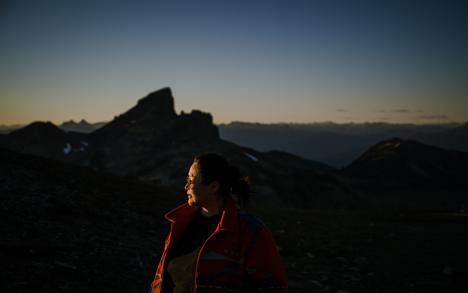 Woman standing in front of the mountains at night.