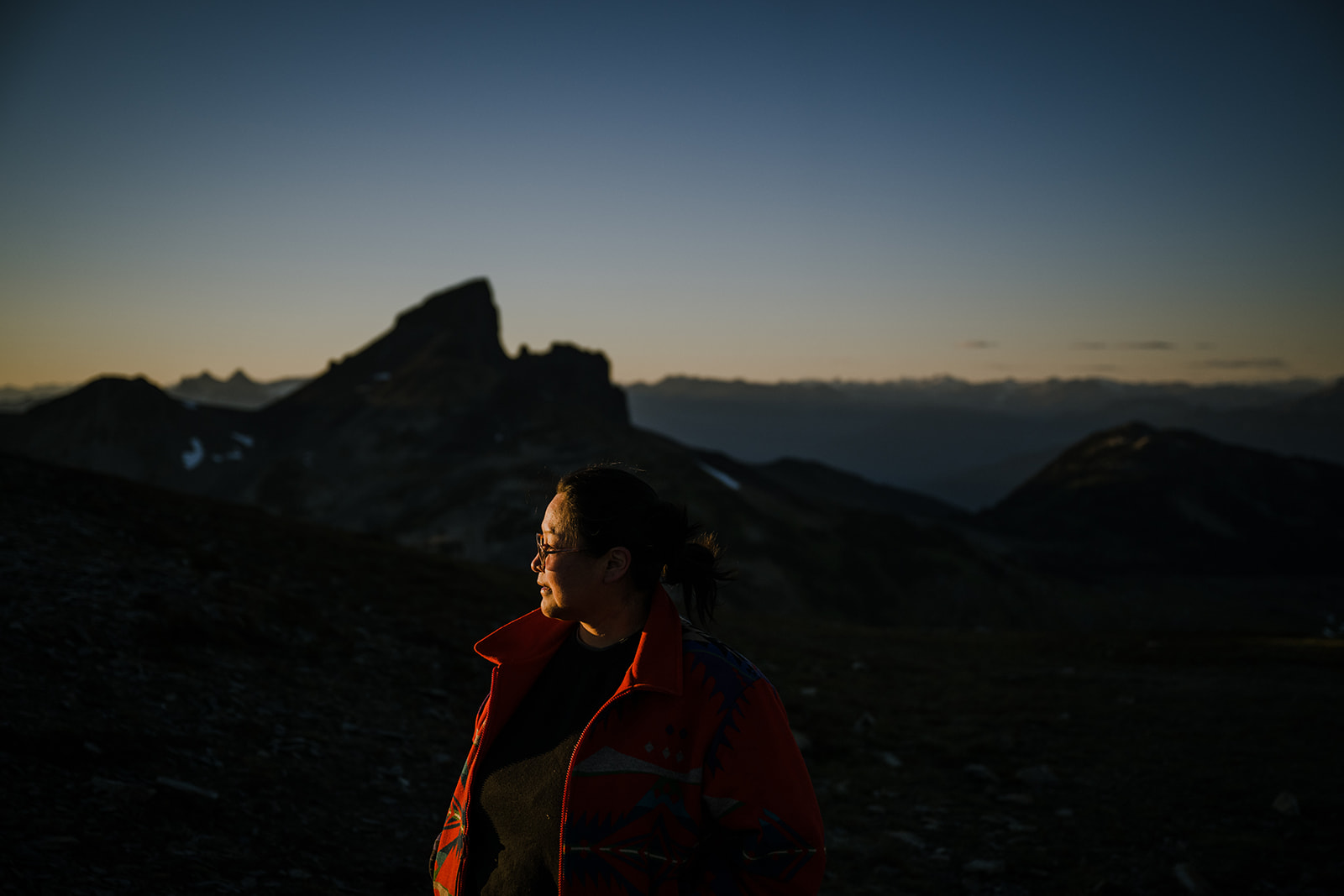 A woman staring into the vast mountain range on top of a mountain