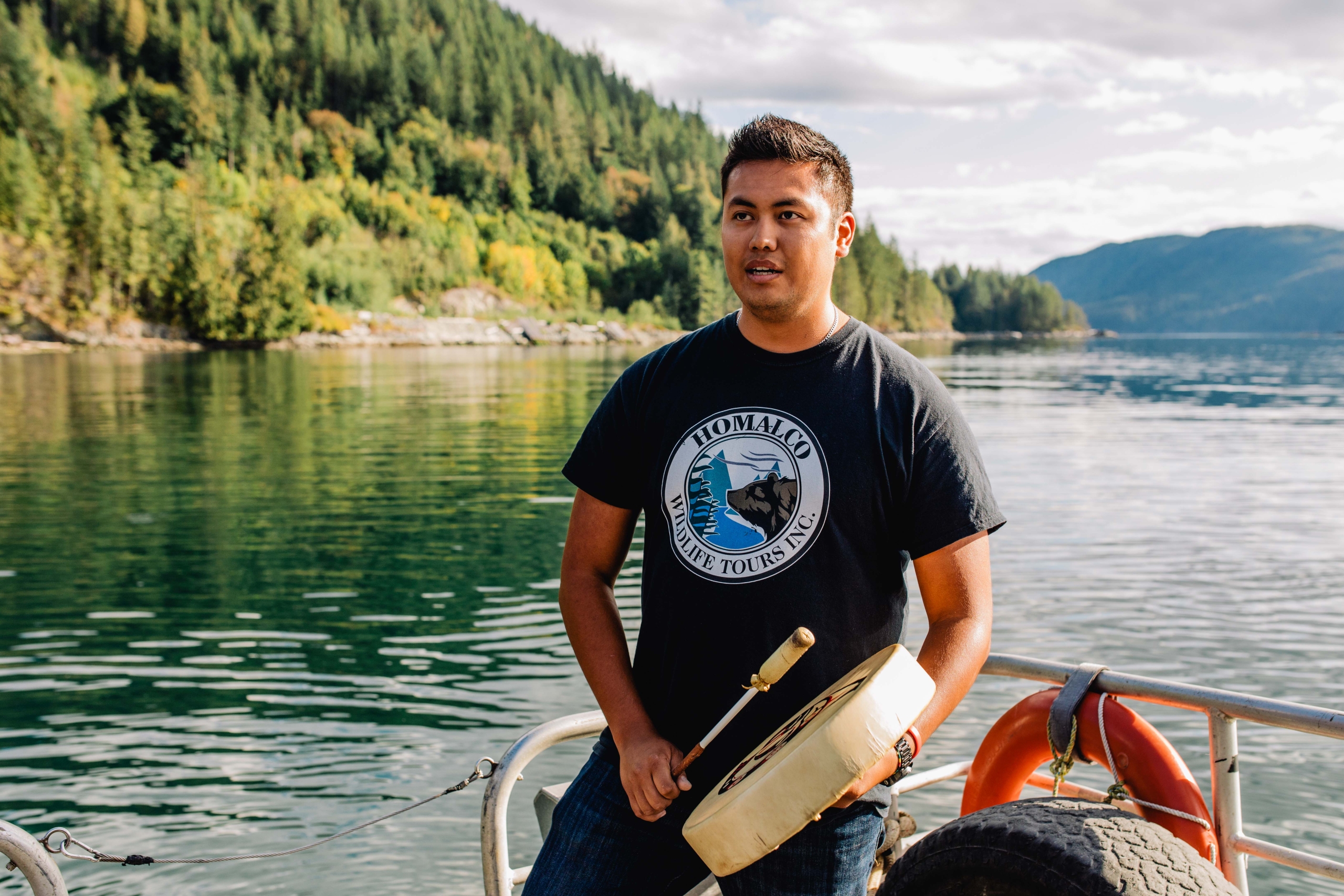 A man standing in a canoe playing the drum