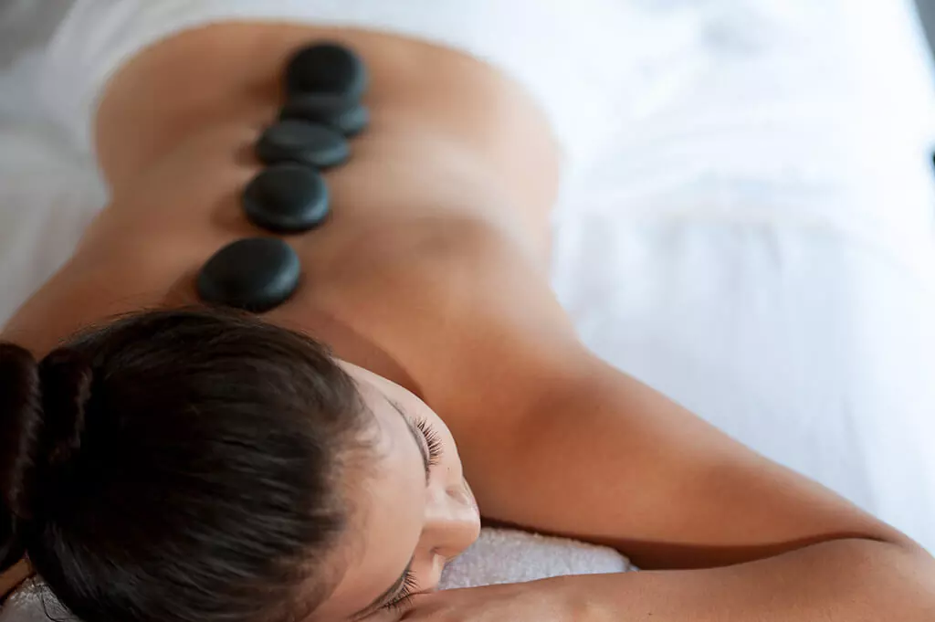 Person with Hot stones. Signature Therapeutic Massage at Rain Wellness Services.