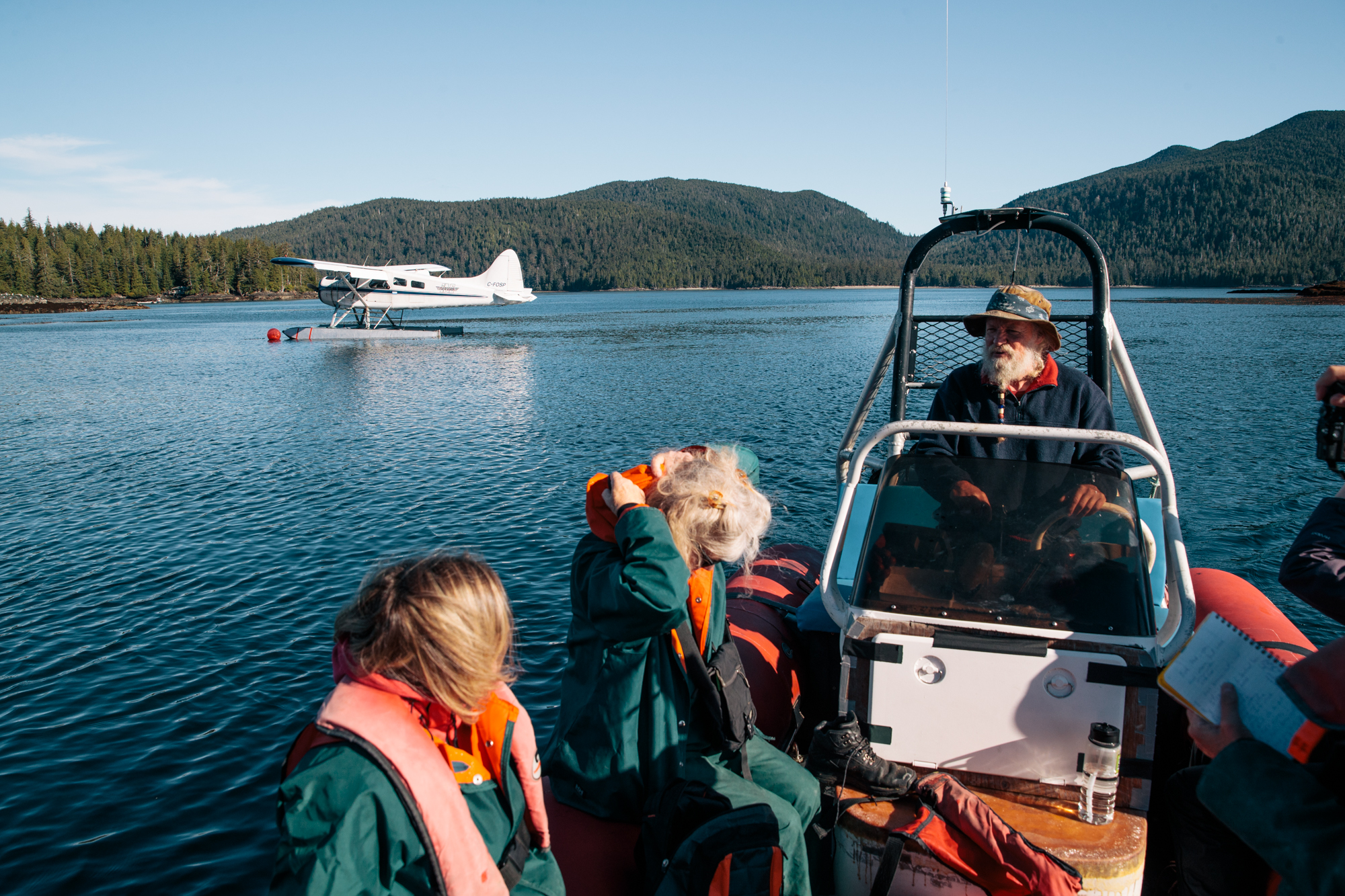 Several people on a boat with. seaplane in the background