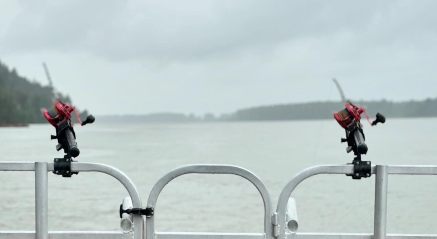 Two fishing lines attached to the end of a fishing boat on water