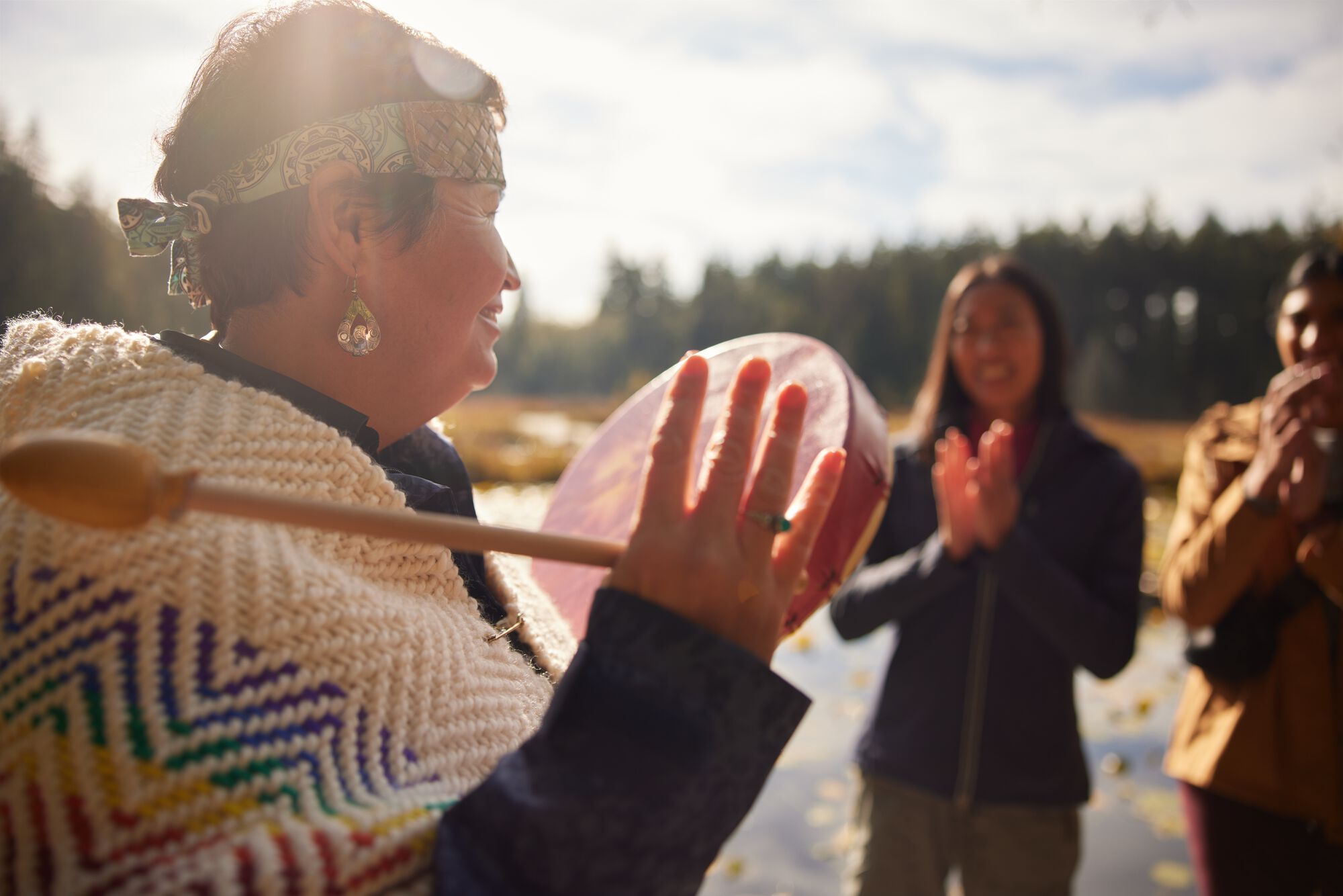 A woman beating on a traditional Indigenous drum