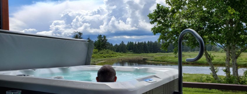 A person in a hot tub overlooking a view of the water