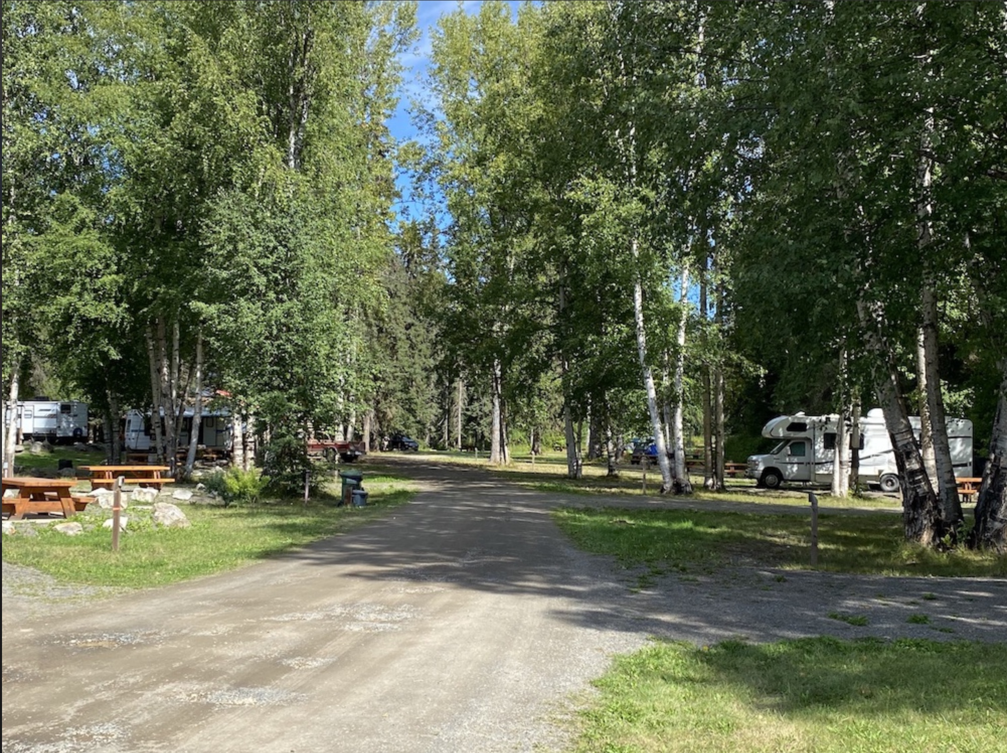 Motor home parked under trees near a picnic table at the Witset RV Park and Campground