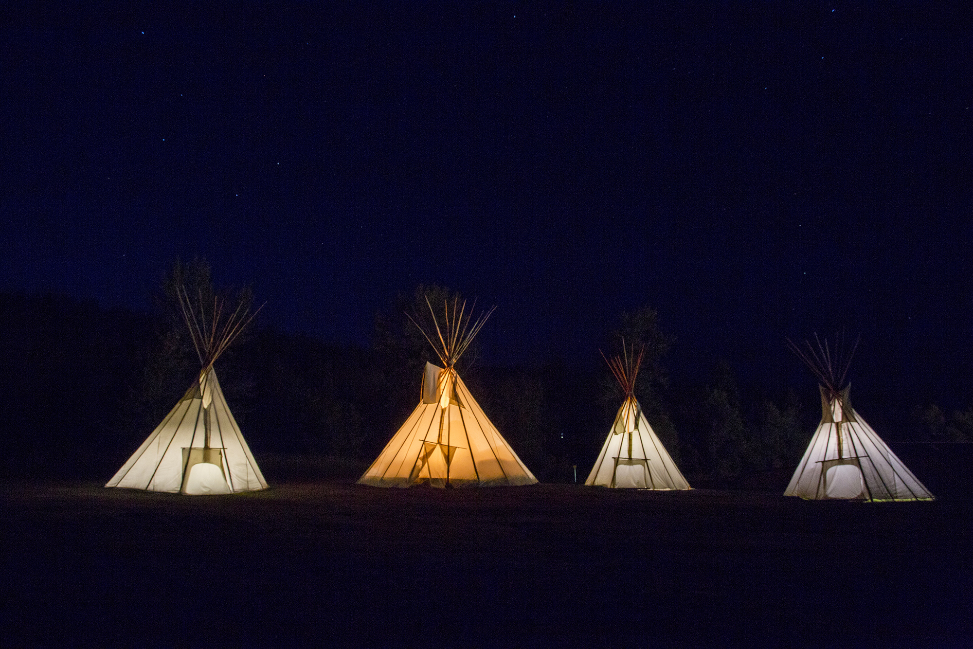 A nighttime view of four teepees