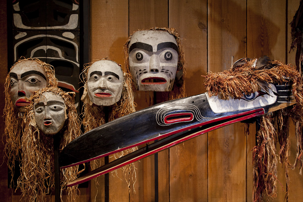 A collection of Indigenous masks hung on a wooden wall