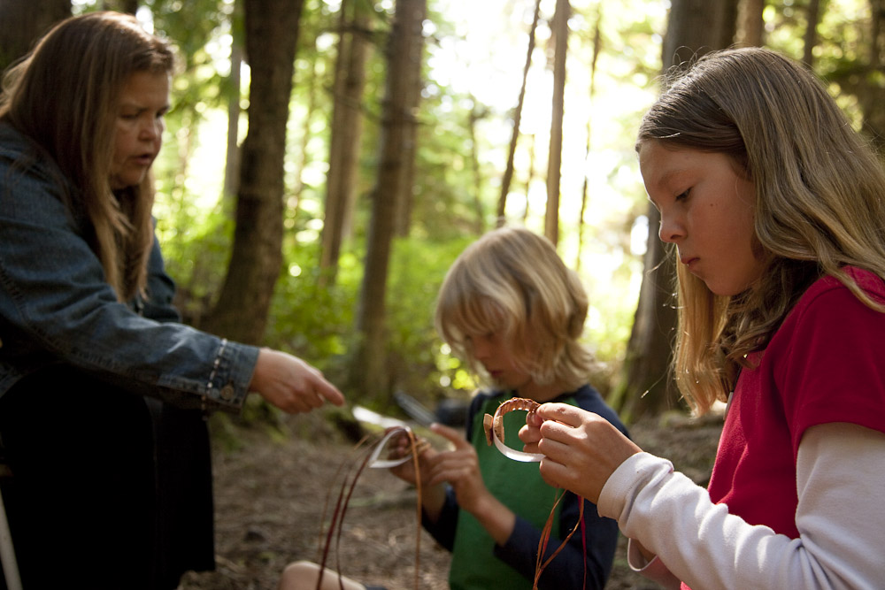 Two children being taught how to weave