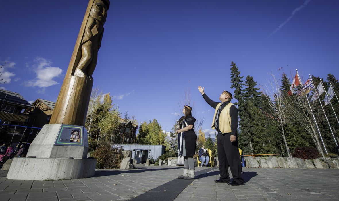 Man and woman looking up at a Totem pole.