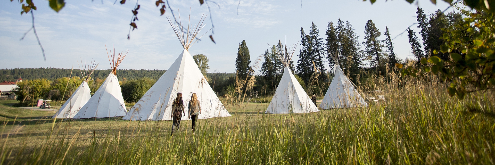 Two people walking towards 5 Teepees.