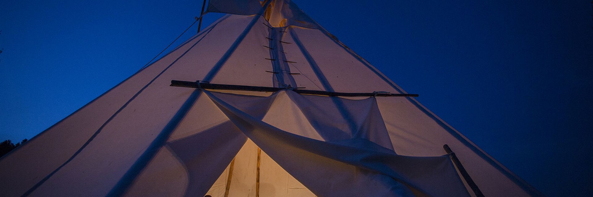 Teepee at night with alight shinning inside.