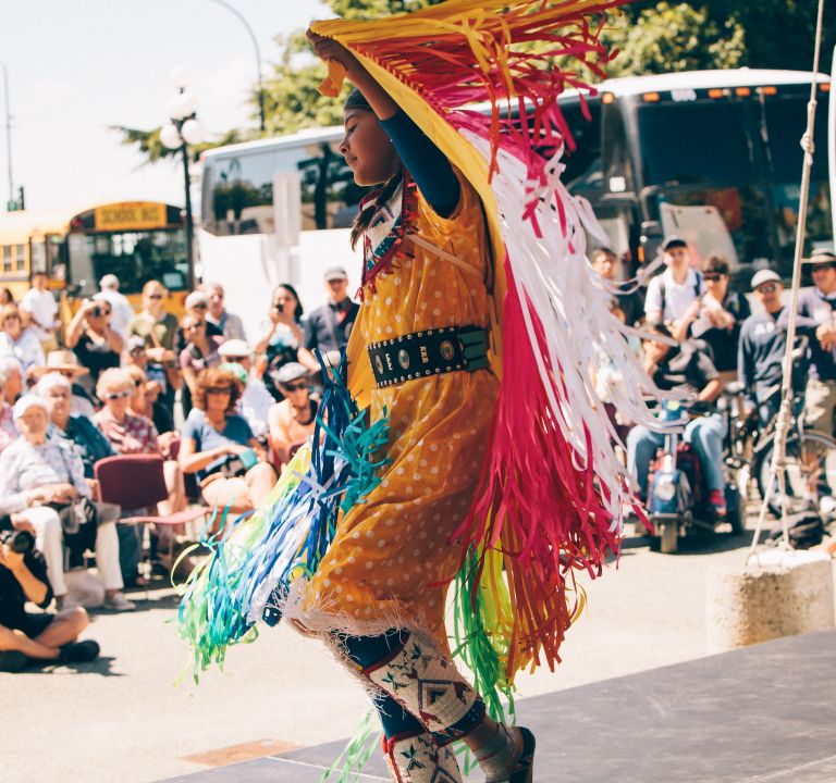 A woman dancing in front of people wearing traditional clothes