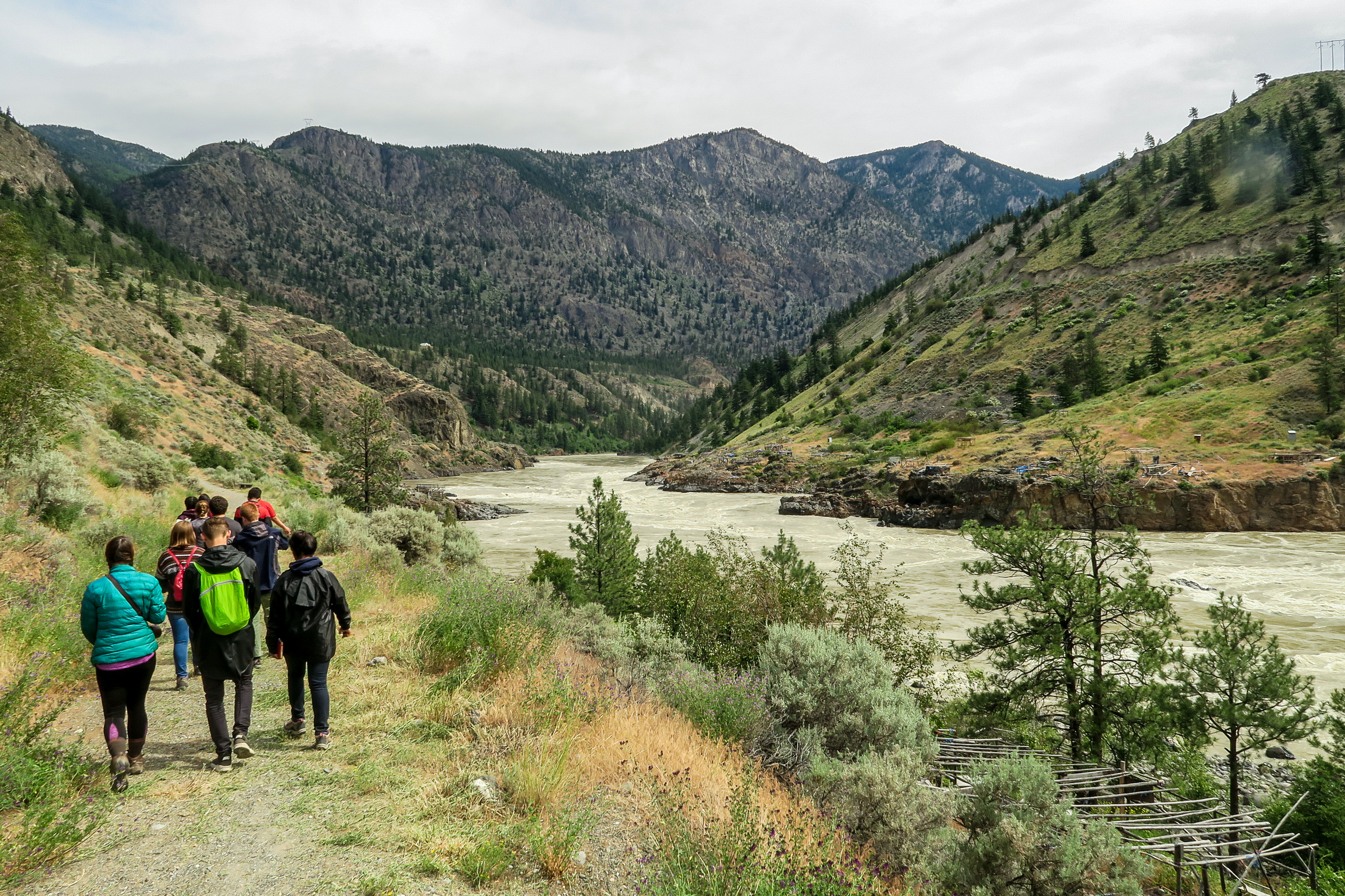 Tourists walking along a river in a valley of the mountains