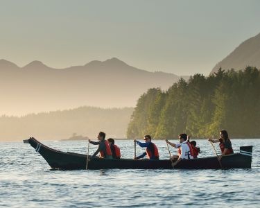 People canoeing in the middle of the lake with mountains in the background.