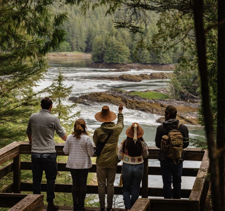 A family looking off of a lookout at a river within the mountains