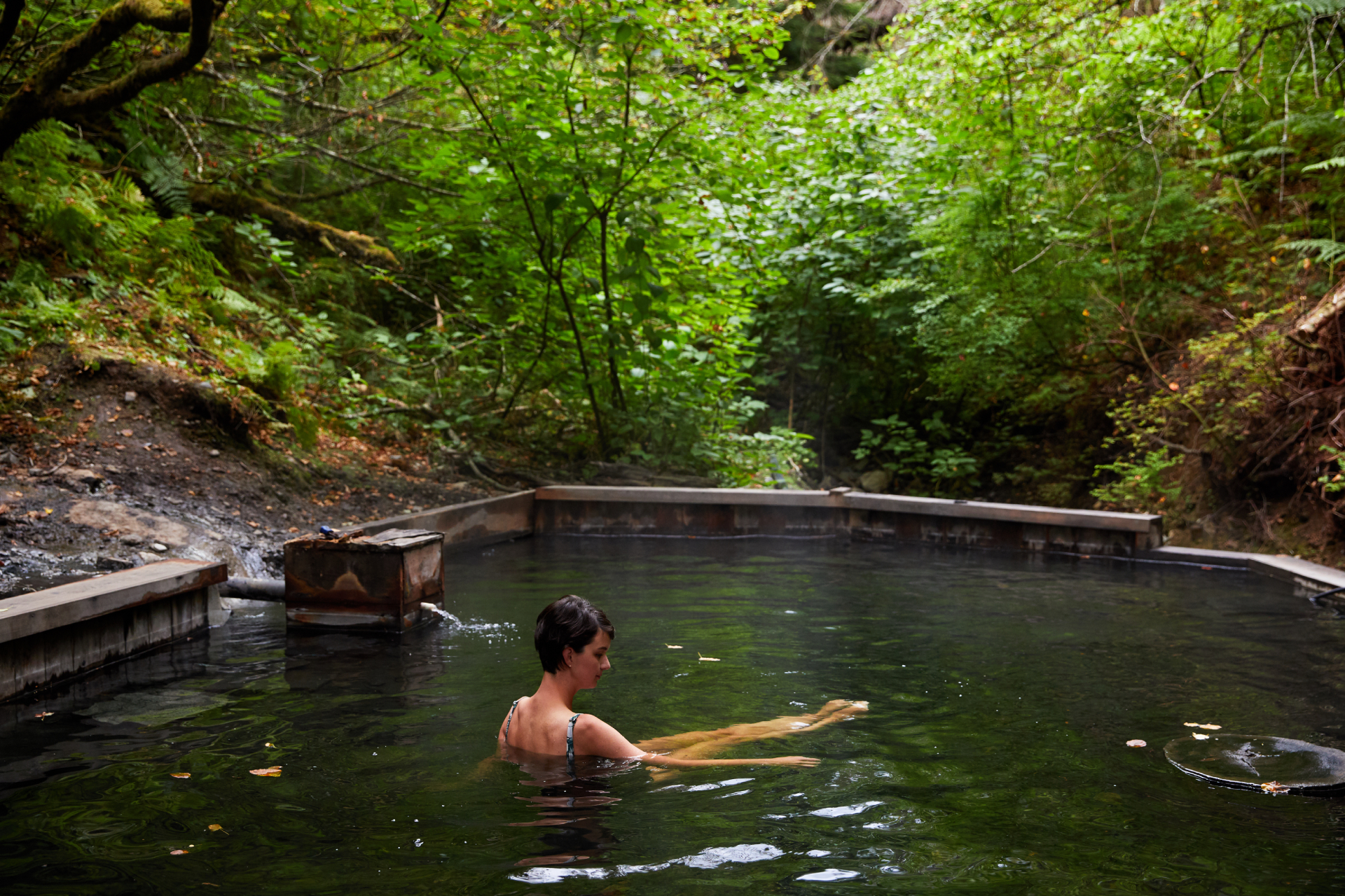 A woman in hot springs stretching her legs.