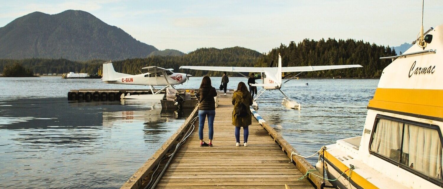 People standing on a dock watching someone getting on a sea plane